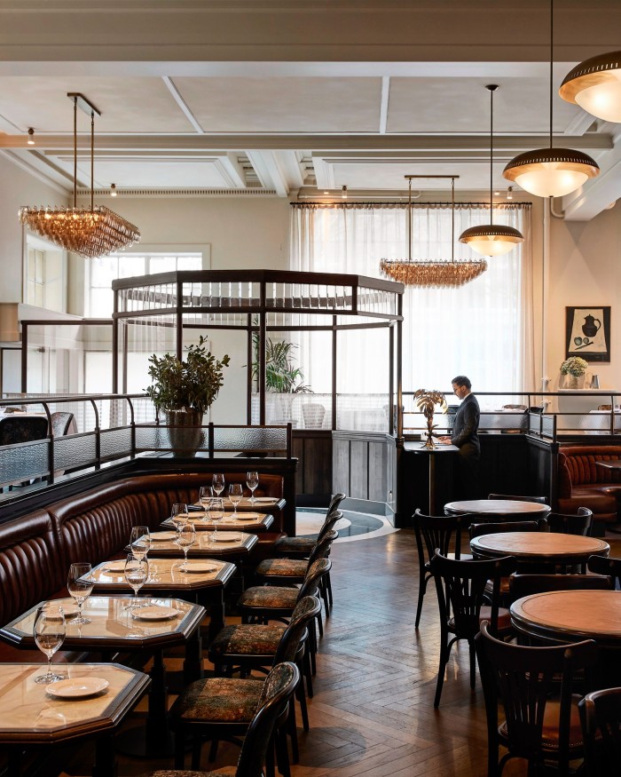 Detail of the dining space at Gimlet restaurant in Melbourne, with rows of dark wooden chairs and brown marble-topped tables