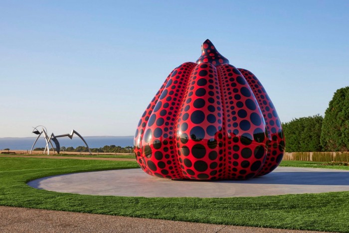 A giant red and black pumpkin sculpture by Yayoi Kusama against a blue sky at Point Fort Estate Sculpture Park